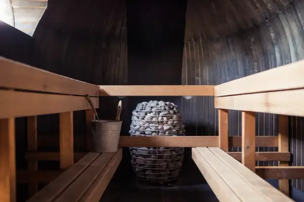 Drewniana sauna z kamiennym piecem. Czy sauna po treningu jest zdrowa? Odpoczynek i regeneracja po wysiłku.