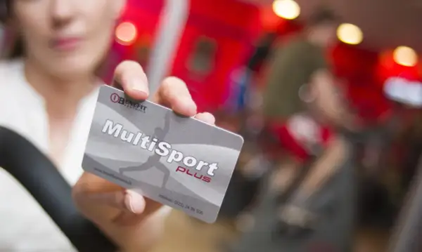 Karta MultiSport Plus w ręce na tle siłowni.